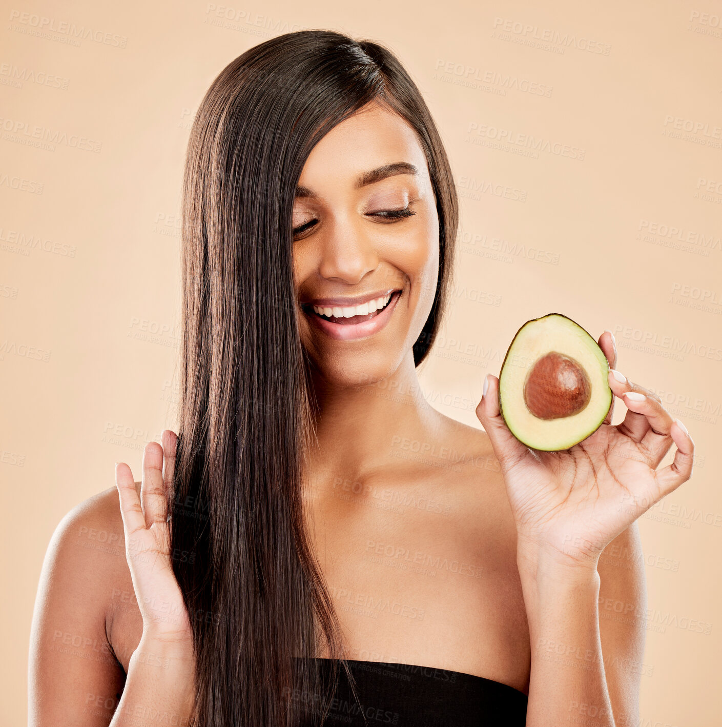Buy stock photo Smile, woman and avocado for hair care, beauty or cosmetic treatment of natural growth on studio background. Happy indian female model, green fruits and vegan dermatology for healthy keratin benefits