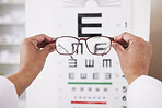 Glasses in hands, optometry and vision, eye care and health with eyesight test and chart, prescription lens and frame. Ophthalmology, focus and healthcare, person in optometrist clinic and eyewear