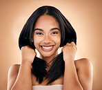 Portrait, hair and skincare with a model woman in studio on a brown background for shampoo treatment. Smile, salon and haircare with a happy young person looking confident about beauty cosmetics