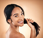 Portrait, strong hair and beauty with a woman in studio on a brown background for shampoo treatment. Face, salon and haircare with a happy young female model looking confident about natural cosmetics