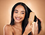 Hair care, brush and happy woman with beauty isolated on a brown background in studio. Salon, smile and model with a wood grooming product for natural aesthetic, hairdresser or hairstyle for wellness