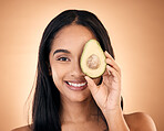 Happy, face and woman with avocado for skincare isolated on a brown background in studio. Portrait, fruit and model with food for nutrition, skin health and vegan diet, omega 3 or natural cosmetics