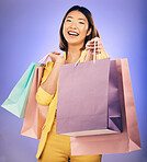 Shopping bag, portrait and woman giving, offer or fashion discount, deal or sale on studio purple background. Giveaway, prize or competition of young customer, model or asian person winning in retail