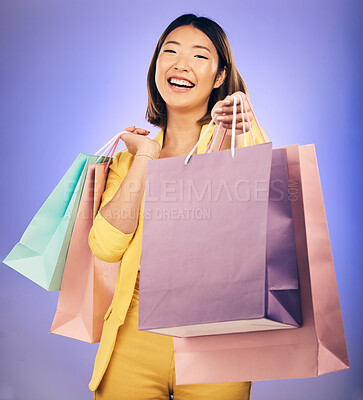Buy stock photo Shopping bag, portrait and woman giving, offer or fashion discount, deal or sale on studio purple background. Giveaway, prize or competition of young customer, model or asian person winning in retail