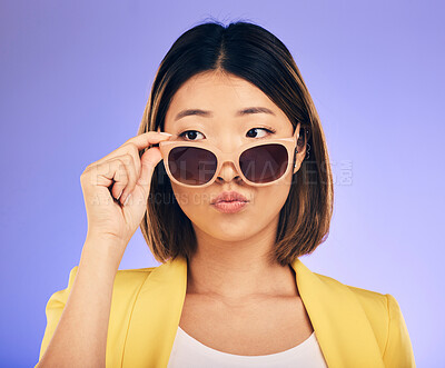 Buy stock photo Fashion, sunglasses and a model asian woman on a purple background in studio for trendy style. Face, shades and attitude with a confident young female person looking over a stylish eyewear frame