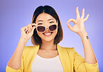 Happy asian woman, portrait and sunglasses, OK sign or fashion accessory against a purple studio background. Female person or model smile with okay gesture in satisfaction for perfect summer style