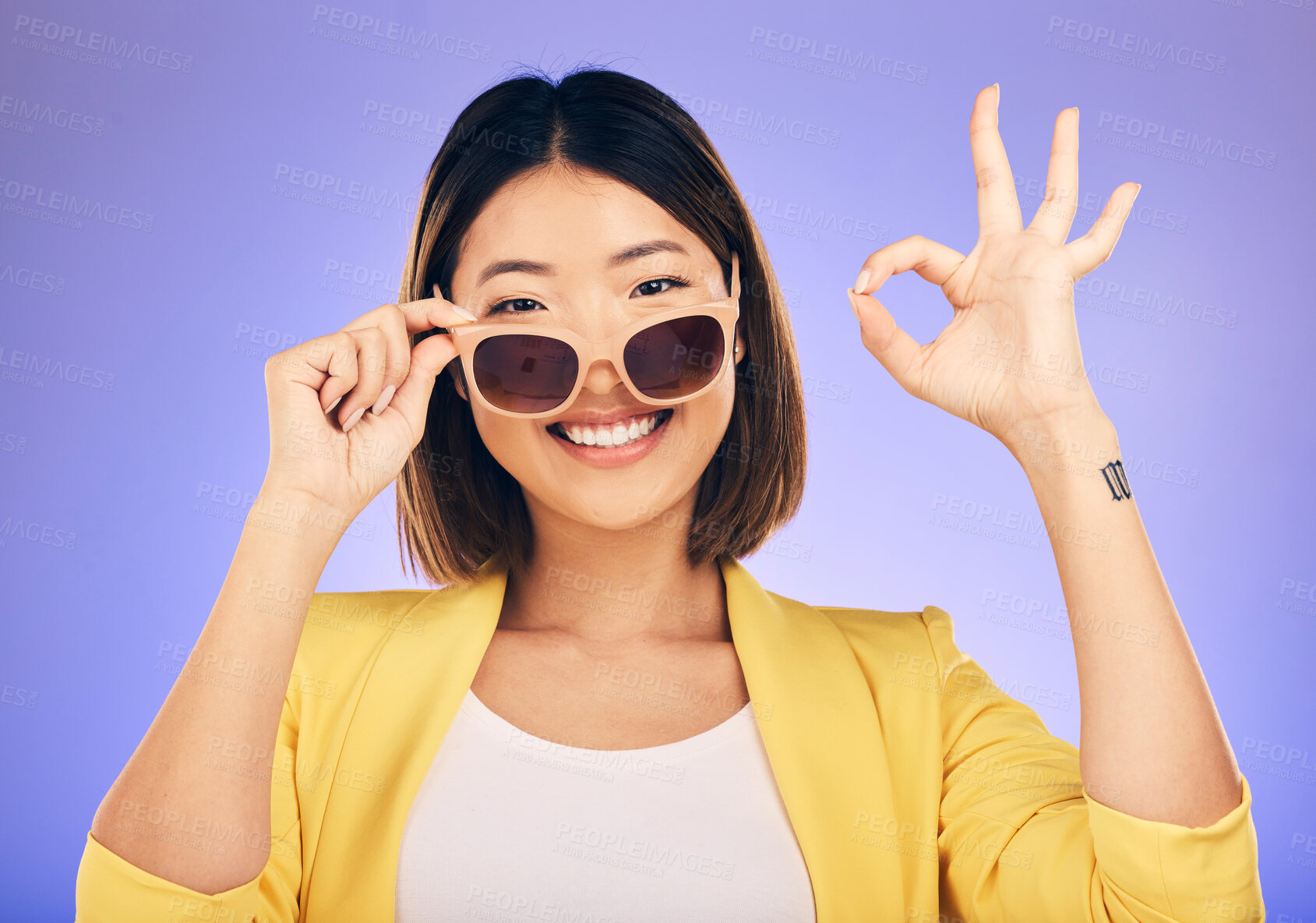 Buy stock photo Happy asian woman, portrait and sunglasses, OK sign or fashion accessory against a purple studio background. Female person or model smile with okay gesture in satisfaction for perfect summer style