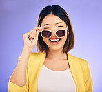 Happy, portrait of asian woman wink with glasses in studio, purple background and fashion. Face, female model and blink emoji with sunglasses for secret, fun personality and gen z girl in good mood