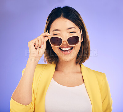 Buy stock photo Happy, portrait of asian woman wink with glasses in studio, purple background and fashion. Face, female model and blink emoji with sunglasses for secret, fun personality and gen z girl in good mood