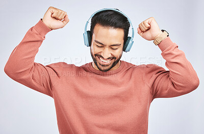 Man, headphones and dance to music in studio, white background and celebrate with energy. Happy, excited and young asian male model listening to audio, streaming sound and hearing rave song on radio