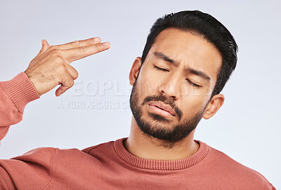 Buy stock photo Depression, face and asian man with hand gun in studio for anxiety, trauma or ptsd on grey background. Finger, suicide and male sad with stress, anxiety or self harm, bipolar or mental health crisis