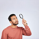 Magnifying glass, confused man and focus in a studio with investigation for clues. Isolated, blue background and male person with inspection for scam, evidence and information search with mockup