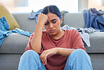 Headache, depression and woman with stress from laundry in a living room, exhausted and unhappy in her home. Anxiety, migraine and female person overwhelmed with household, task or spring cleaning