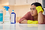 Cleaning, spray bottle and frown with an annoyed woman housekeeper looking at hygiene products in the kitchen. Depression, housekeeping and supplies with a frustrated female cleaner in a home