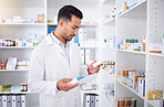 Medicine inspection, pharmacy and man with a note for medical stock or healthcare in store. Retail, work and male Asian pharmacist reading information on a box of pills with a document for inventory