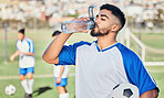 Football, athlete and man drinking water outdoor on a field for sports and fitness competition. Tired male soccer player or athlete person on break while exhausted from challenge or training workout