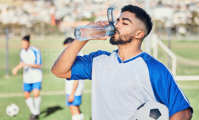 Buy stock photo Football, athlete and man drinking water outdoor on a sports field for fitness competition. Tired male soccer player on a break and exhausted from exercise, challenge or training workout for health