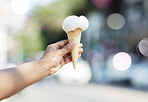 Hands, person and ice cream cone in city for dessert, cool snack and sweet food to enjoy outdoor. Closeup, scoop and frozen vanilla gelato in summer, travel and sunshine of urban town, street or trip