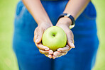 Woman, hands and apple for natural nutrition, diet or food in health and wellness in nature outdoors. Closeup of female person holding organic fruit in palm for sustainability, vitamin or fiber meal