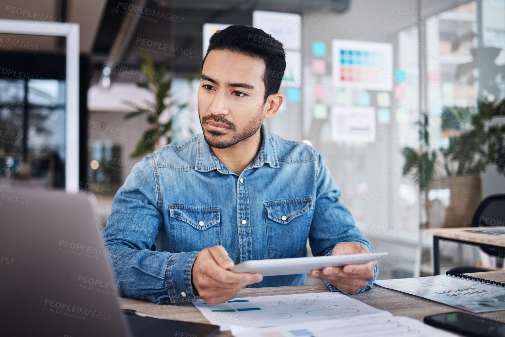 Buy stock photo Thinking, tablet and man at desk with paperwork, notes and research planning at design agency. Business, documents and computer, employee in office reading email or online report at tech startup job.