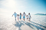 Water, beach and happy family walking at the sea or ocean bonding for love, care and happiness together. Happy, sun and parents with children or kids and grandparents on a holiday for freedom