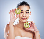 Beauty, portrait and woman with kiwi in studio for a natural, organic or health face routine. Skincare, self care and female model with fresh fruit for facial dermatology treatment by gray background