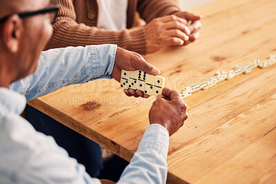 Buy stock photo Hands, dominoes and a senior man playing a game at a table in the living room of a retirement home. Thinking, strategy and fun with an elderly male pensioner in a house closeup for entertainment