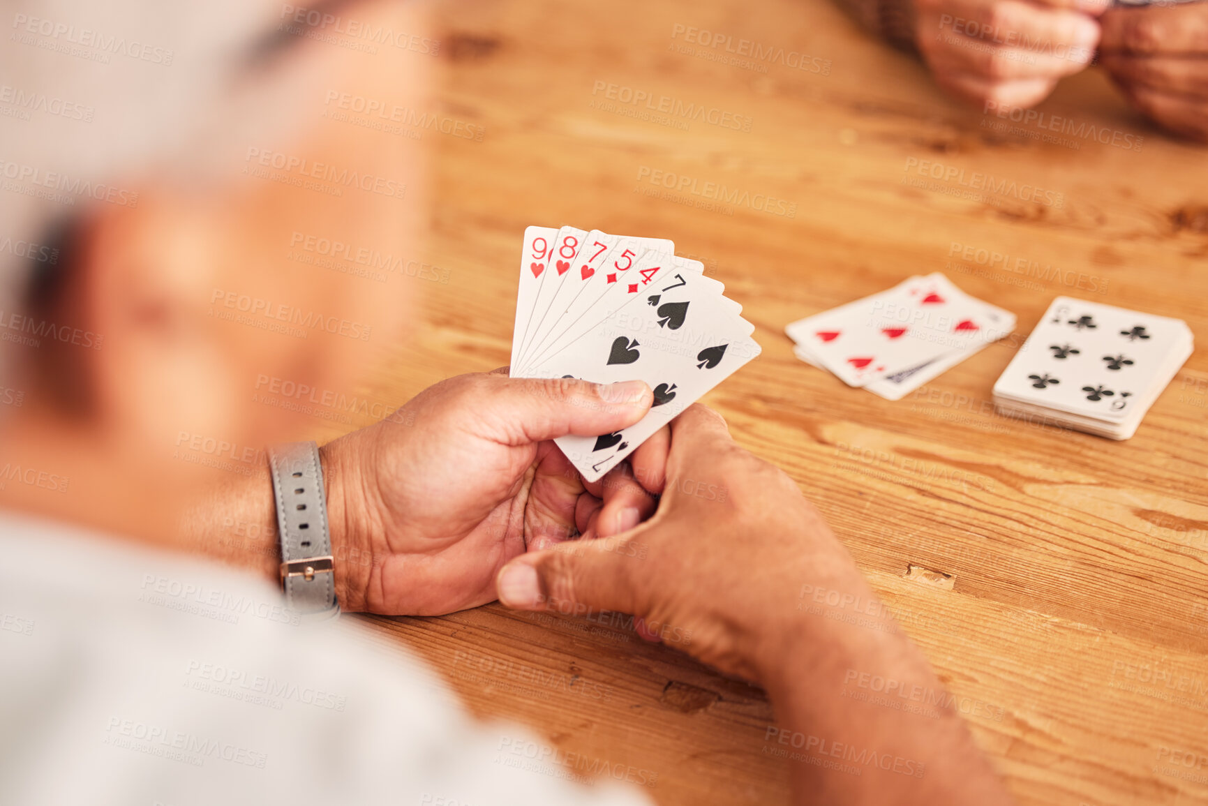 Buy stock photo Hands, cards and a senior man playing poker at a table in the living room of a retirement home. Gambling, planning and fun with an elderly male pensioner in a house closeup for entertainment games