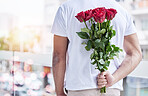 Love, surprise and man with roses behind back for date, romance and hope for valentines day. Romantic confession, floral gift and person with bouquet of flowers in city for proposal or engagement.