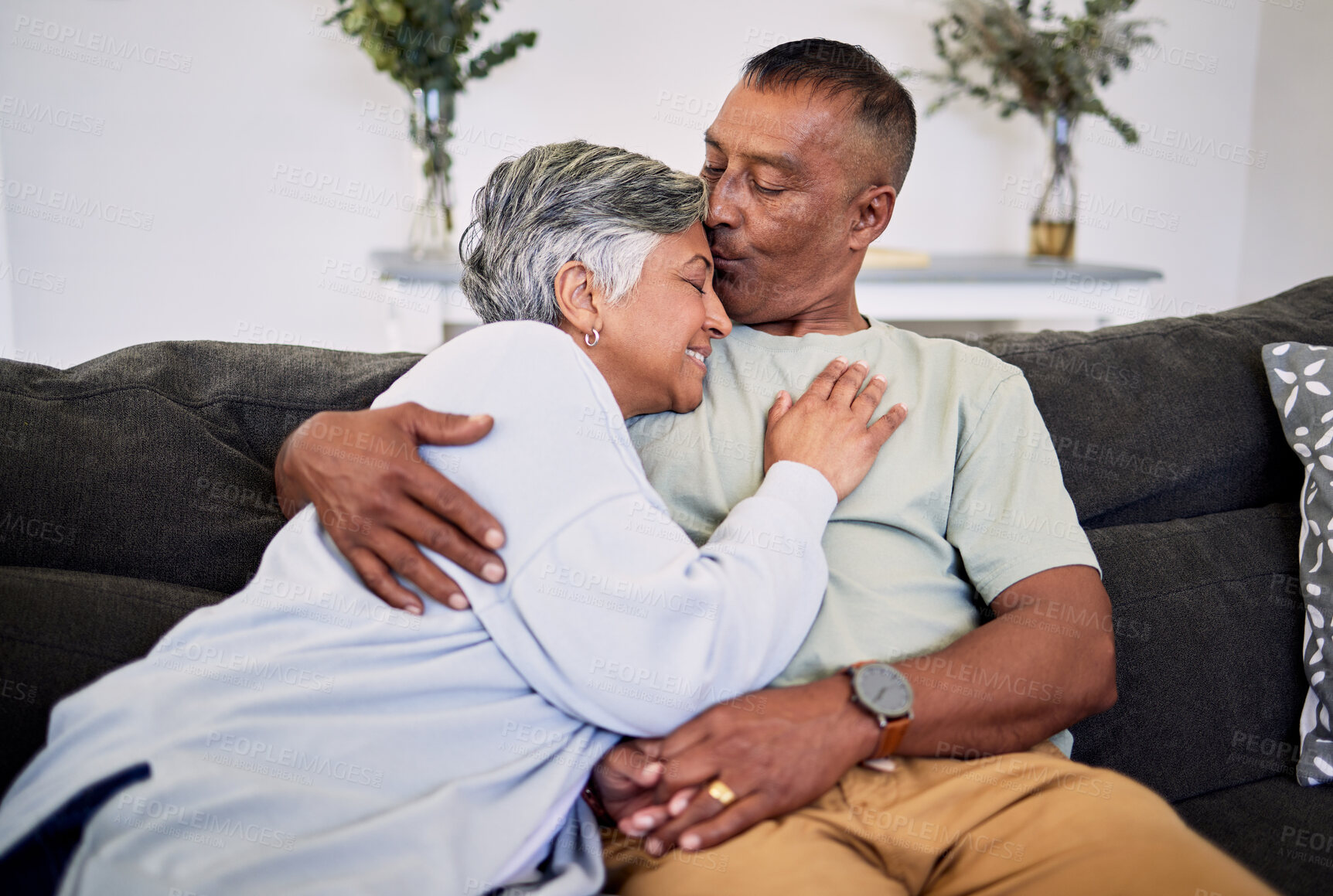 Buy stock photo Love kiss, home or elderly couple smile, hug and enjoy quality time together, care or romance on lounge couch. Marriage support, living room sofa or senior husband, old wife or bonding people embrace