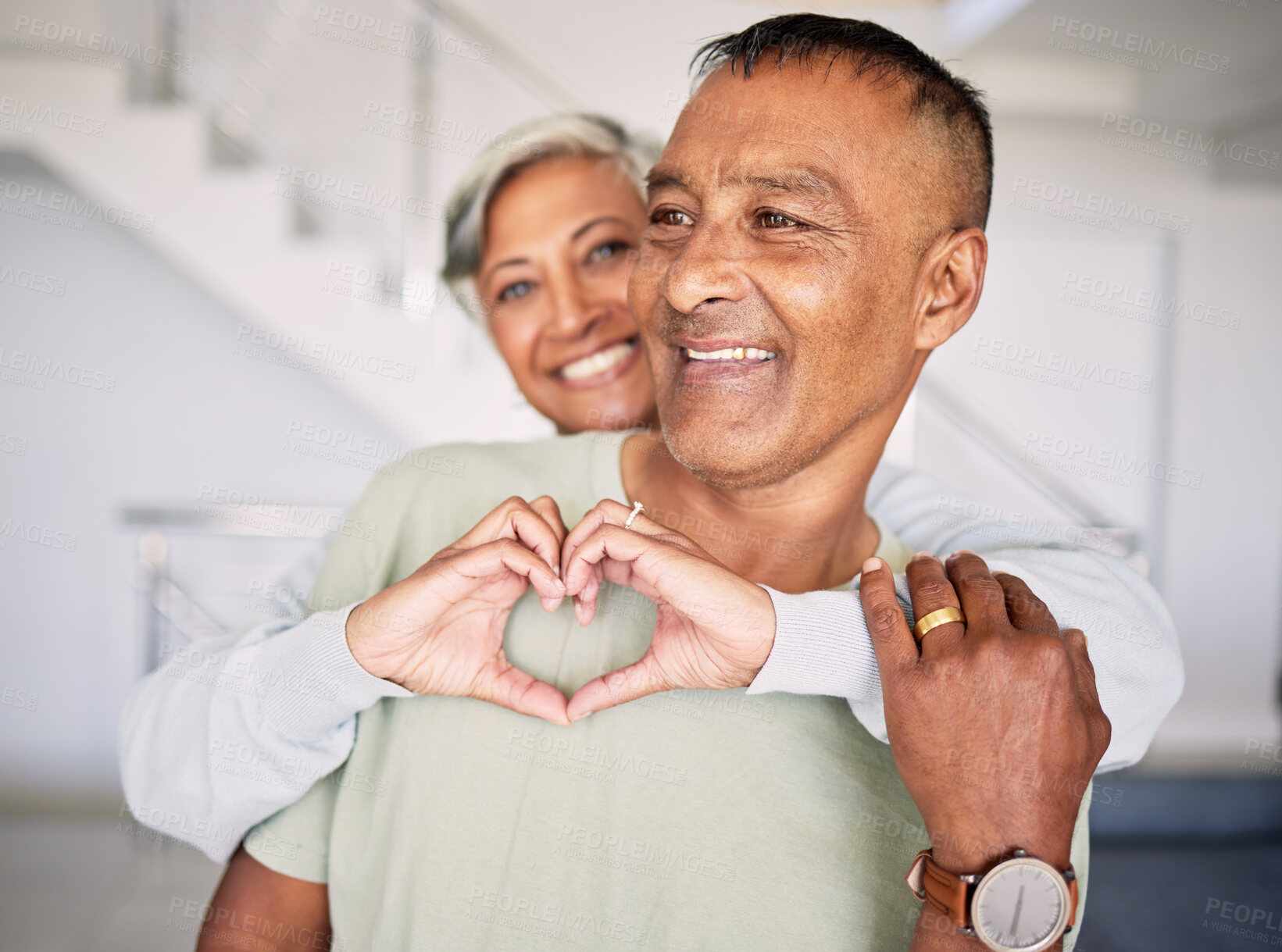 Buy stock photo Heart, hands and couple in home for love, kindness and commitment to life partner, relationship or emoji sign. Mature, man, happy woman and hug with finger shape of care, support or trust in marriage