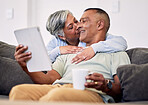 Senior couple, hug and tablet on sofa to relax with quality time in home with bonding during retirement. Couple, technology and embrace with elderly man or woman in living room together on couch.