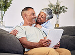 Love, happy and senior couple with tablet on the sofa networking on social media or the internet. Smile, relax and elderly man and woman in retirement networking on digital technology in living room.