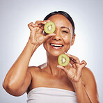 Skincare, face and mature woman with kiwi in studio isolated on a white background. Food, natural fruit and portrait of happy model with nutrition for wellness, healthy diet and beauty for anti aging