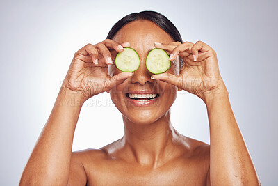 Buy stock photo Cucumber, face and natural beauty of happy woman in studio, white background and healthy diet. Female model, skincare and fruits on eyes for sustainable cosmetics, aesthetic dermatology and nutrition