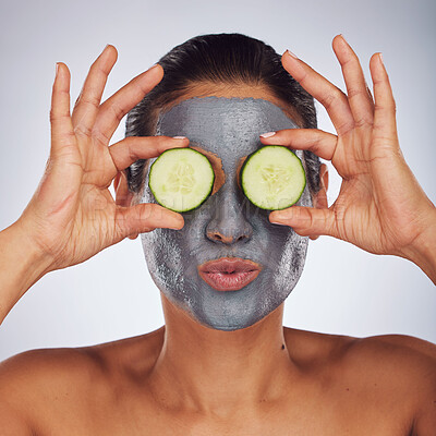 Buy stock photo Eyes, cucumber and mask with a model woman in studio on a gray background for an antiaging facial treatment. Face, skincare and food with a young female person using cosmetic clay on her face