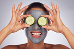 Facial, cucumber and mask with a model woman in studio on a gray background for an antiaging face treatment. Eyes, skincare and food with a happy young female person using cosmetic clay on her face