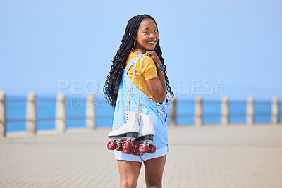 Portrait, back and roller skating with a black woman by the sea, on the promenade for training or recreation. Beach, sports or fun with a happy young teenager holding skates on the coast by the ocean