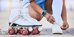 Hands, roller skates and tie shoes on street to start exercise, workout or training outdoor. Skating, person and tying sneakers to get ready for sports on road to travel, journey and fitness practice