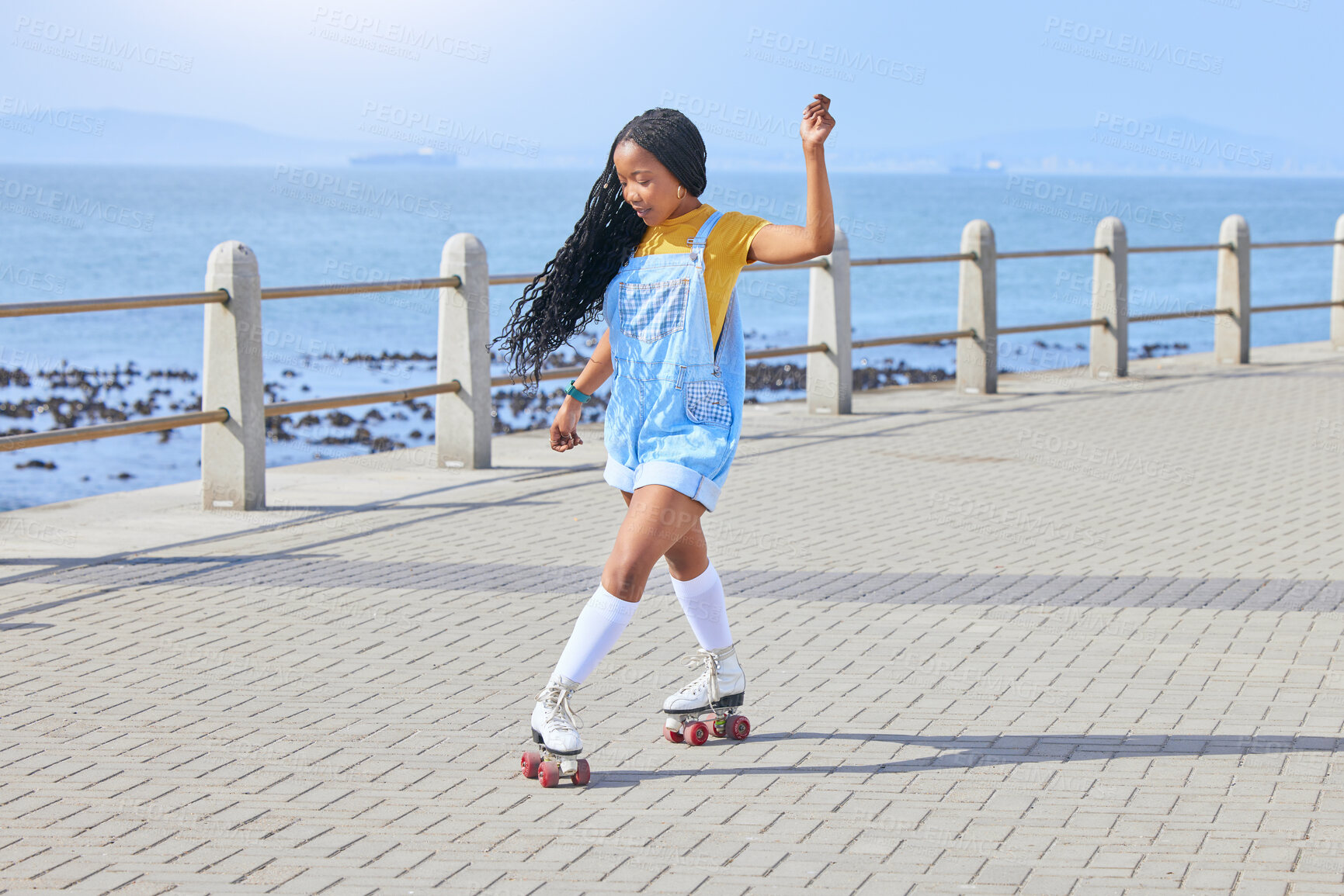 Buy stock photo Roller skating, fun or freedom with a black woman by the sea, on the promenade for training or recreation. Beach, sports and a young female teenager in skates on the coast by the ocean or water