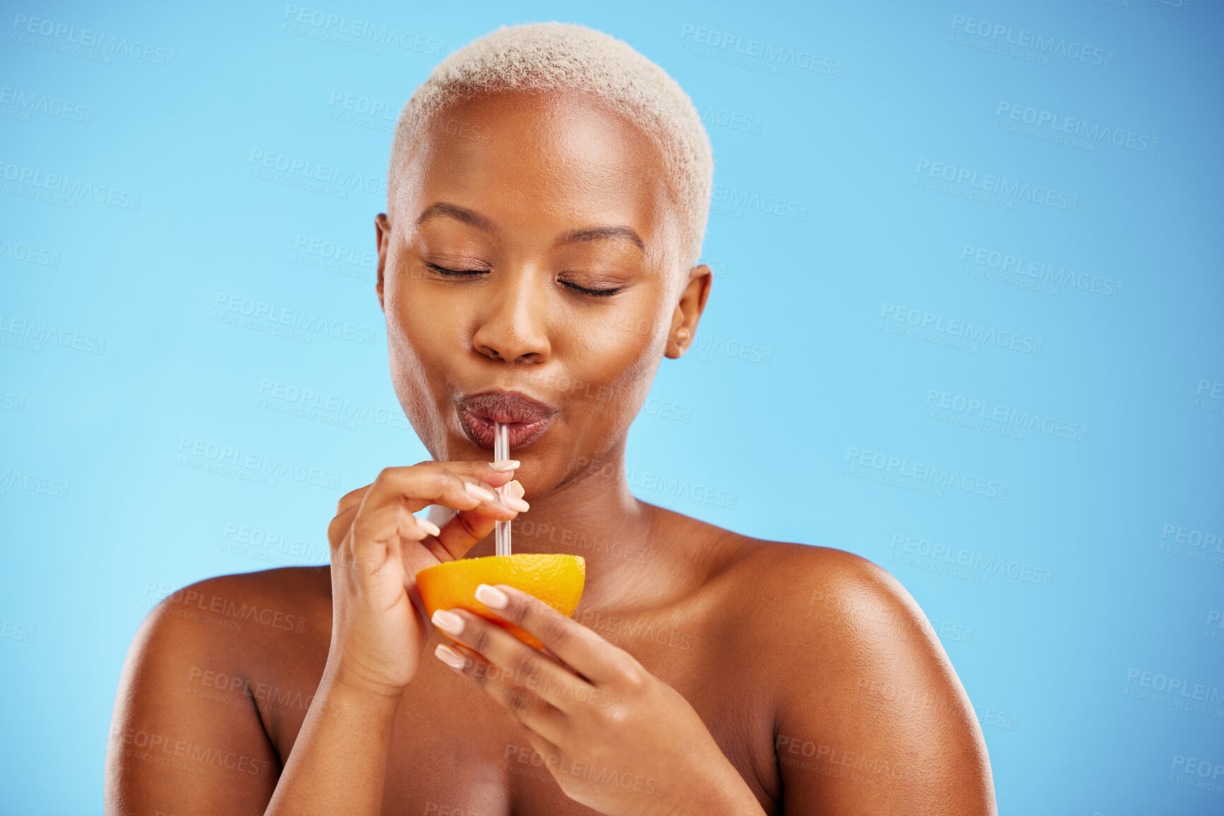 Buy stock photo Black woman, vitamin C and drinking orange for diet or natural nutrition against a blue studio background. Calm African female person with citrus fruit, drink and straw for healthy wellness or juice
