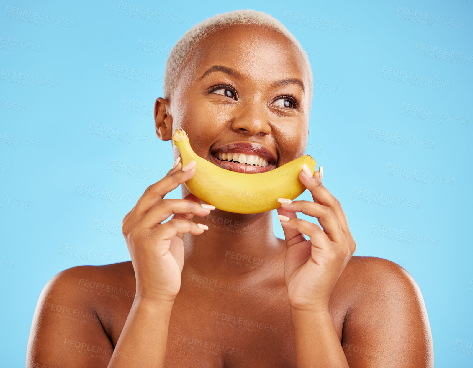 Buy stock photo Beauty, smile and banana with a model black woman thinking on a blue background in studio. Skincare, idea and food with a happy young female person holding yellow fruit for natural wellness or detox