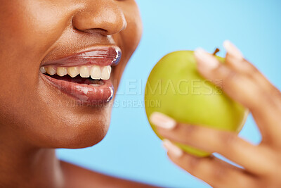 Buy stock photo Black woman, mouth and apple in diet, nutrition or health and wellness against a blue studio background. Closeup of African female person eating natural organic fruit for vitamin, fiber or food snack