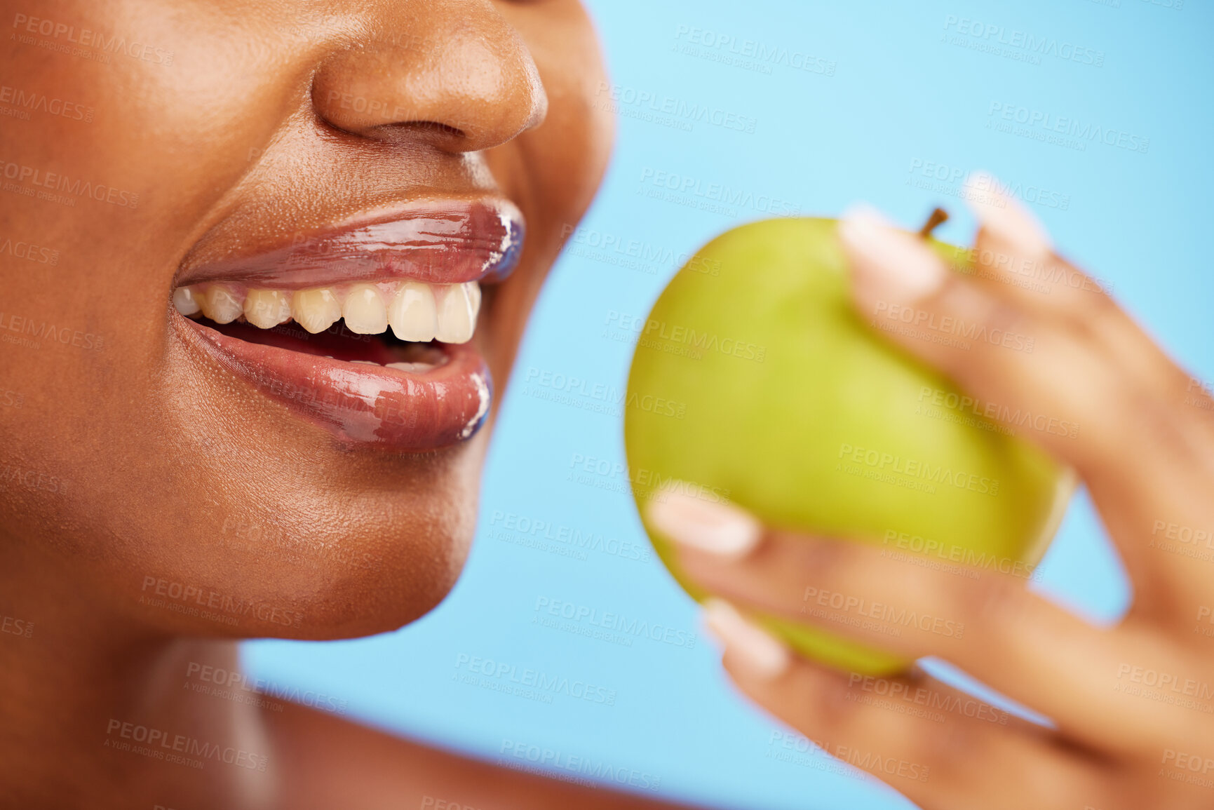 Buy stock photo Black woman, mouth and apple in diet, nutrition or health and wellness against a blue studio background. Closeup of African female person eating natural organic fruit for vitamin, fiber or food snack