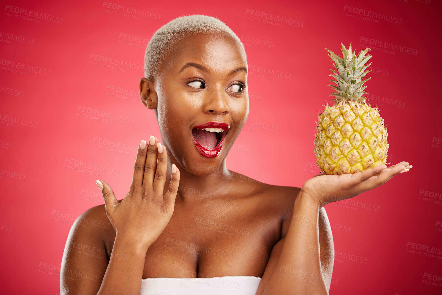 Buy stock photo Pineapple, surprise and beauty of a woman in studio for healthy food, diet or fruit. Black female model with makeup on red background for wellness glow, natural cosmetics and wow skin care benefits