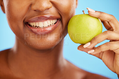 Buy stock photo Woman, smile and apple for diet, nutrition or health and wellness against a blue studio background. Closeup of female person mouth with natural organic green fruit for vitamin, fiber or food snack