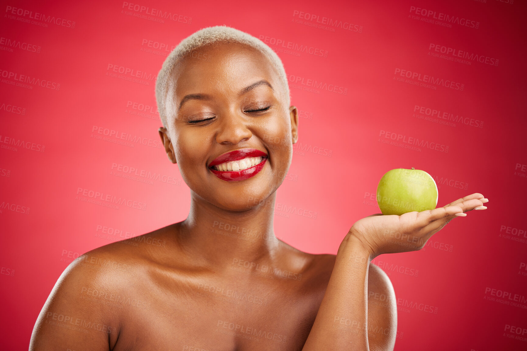 Buy stock photo Happy black woman, apple and natural nutrition for healthy diet against a red studio background. African female person smile with natural organic green fruit for food snack, health and wellness