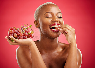 Buy stock photo Health, eating and a black woman with grapes on a red background for nutrition or diet. Smile, beauty and an African model or girl with fruit, hungry and food for a detox isolated on a backdrop