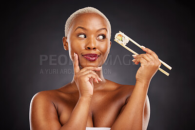 Buy stock photo Sushi, thinking and face of a woman with chopsticks in studio for healthy eating, beauty or food. Black female model with makeup on dark background for wellness glow, diet or seafood advertising idea