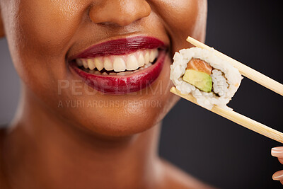 Buy stock photo Mouth, eating and woman with sushi and chopsticks in studio for healthy food or teeth. Black female model with makeup on dark background for wellness glow, diet and seafood or salmon closeup
